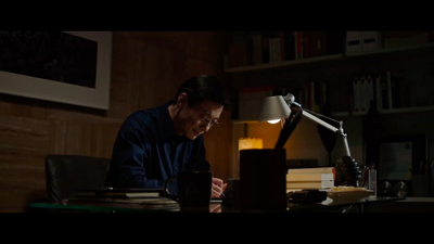 a man sitting at a desk in front of a lamp