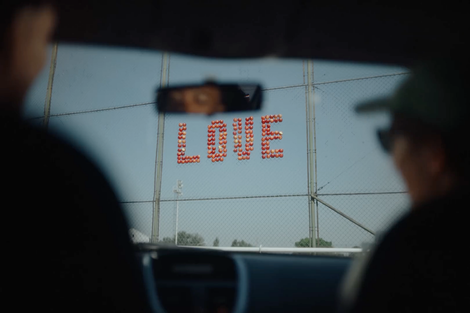 a sign that reads love on the side of a fence