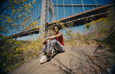 a woman sitting on a rock in front of a bridge