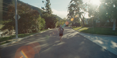 a man walking down a street next to a forest