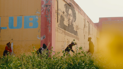 a group of people walking past a yellow building