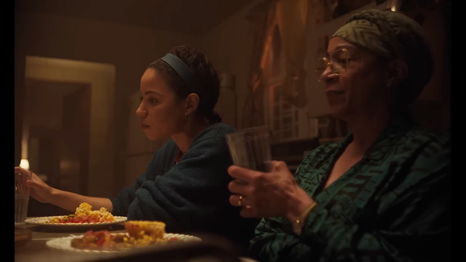 two women sitting at a table with plates of food