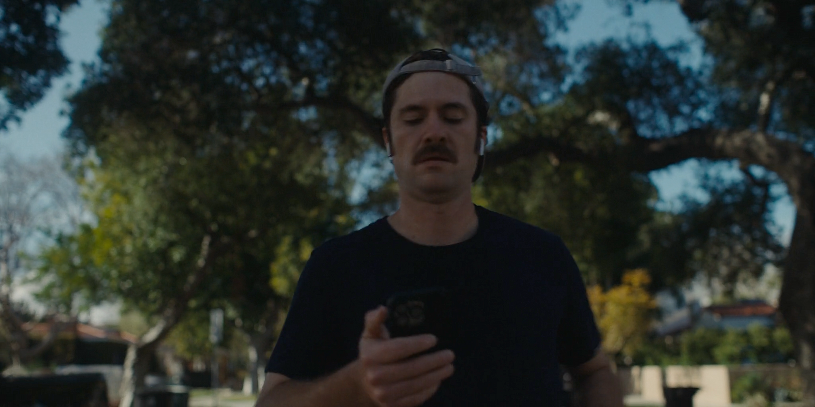 a man standing in a park looking at his cell phone