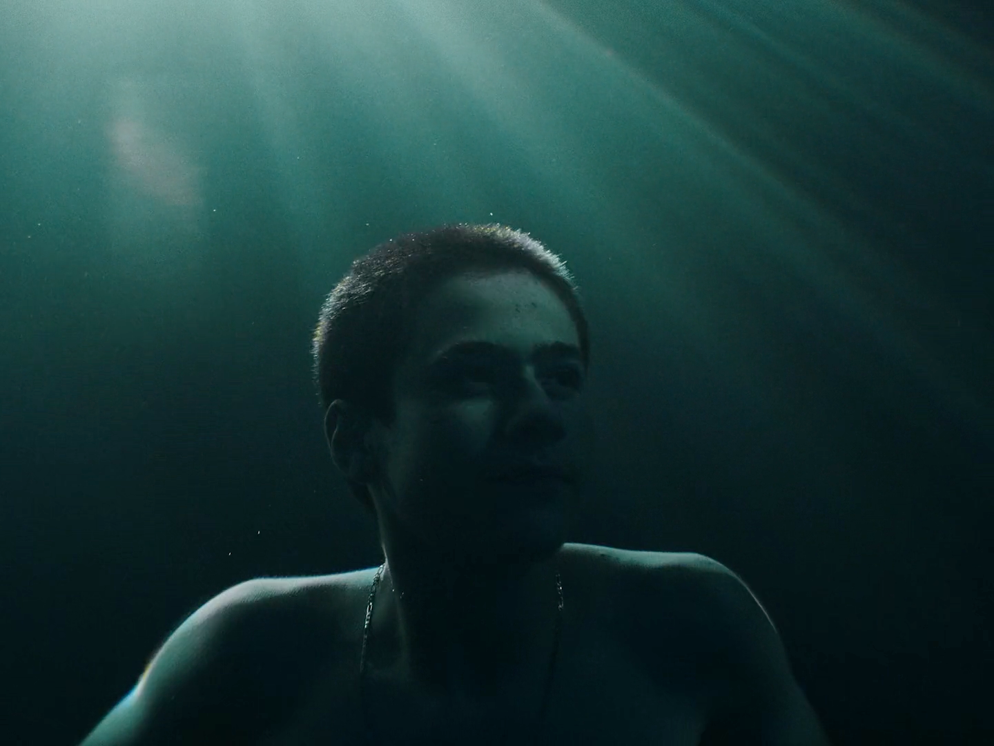 a woman in a dark room with sunlight streaming through the water