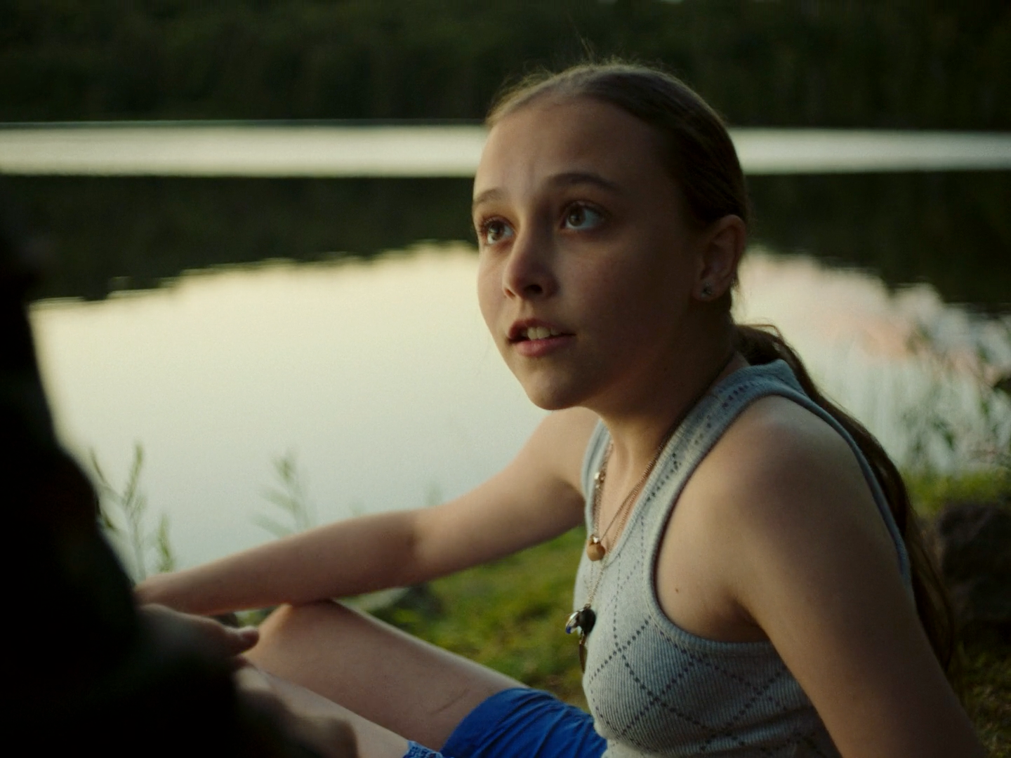 a woman sitting on the ground next to a body of water