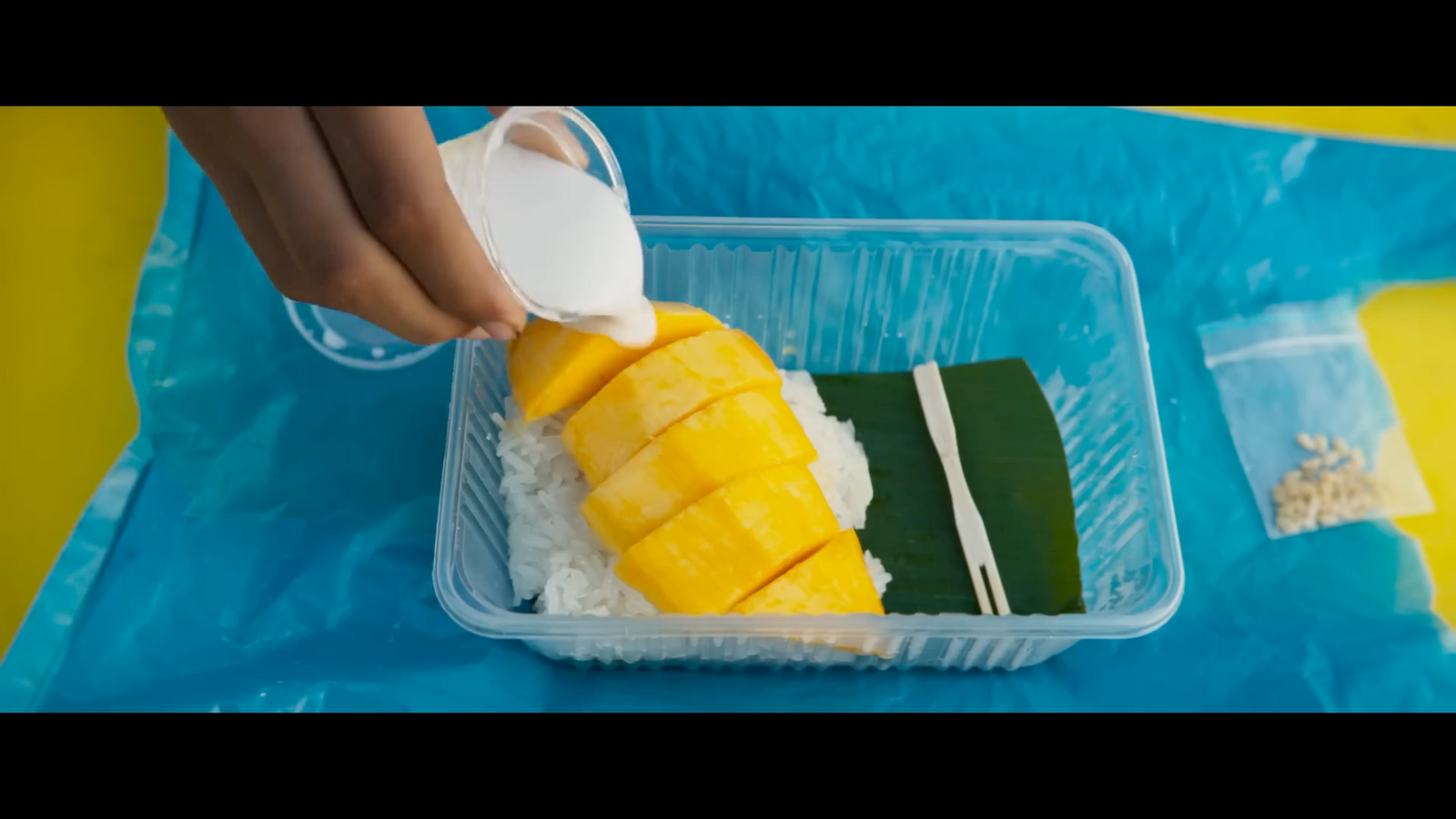 a plastic container filled with rice and sliced mangoes