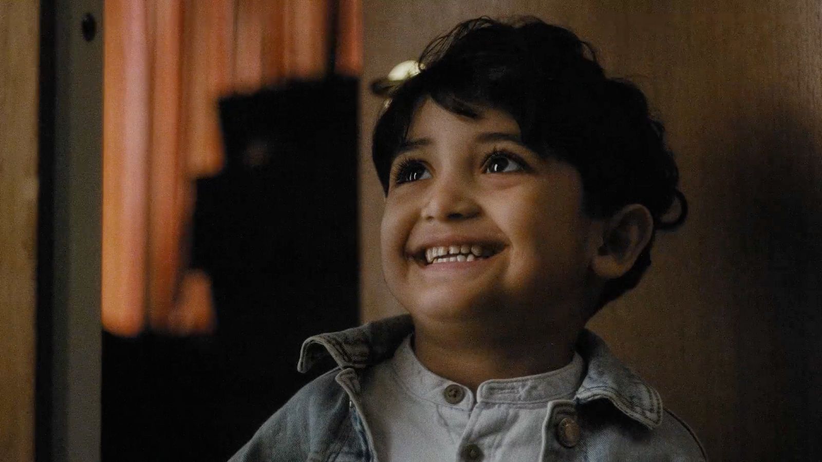 a young boy smiling in front of a door