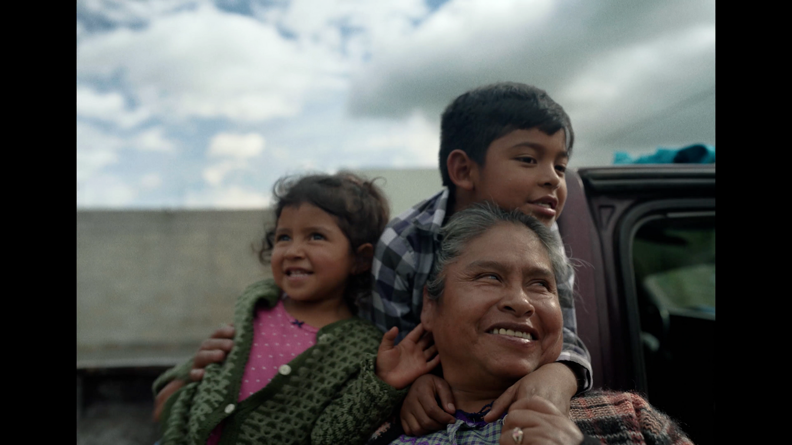 a man and two children sitting on the back of a truck