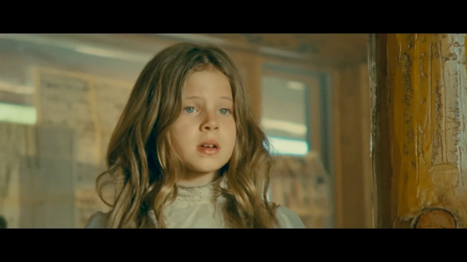 a little girl with long hair standing in front of a door