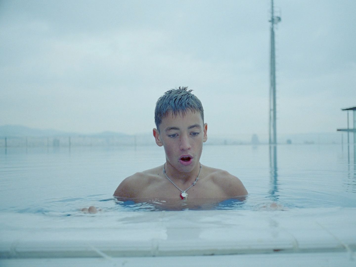 a man in a pool with a necklace on his neck