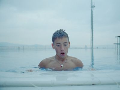 a man in a pool with a necklace on his neck