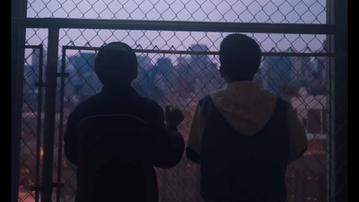 a couple of men standing next to each other near a fence