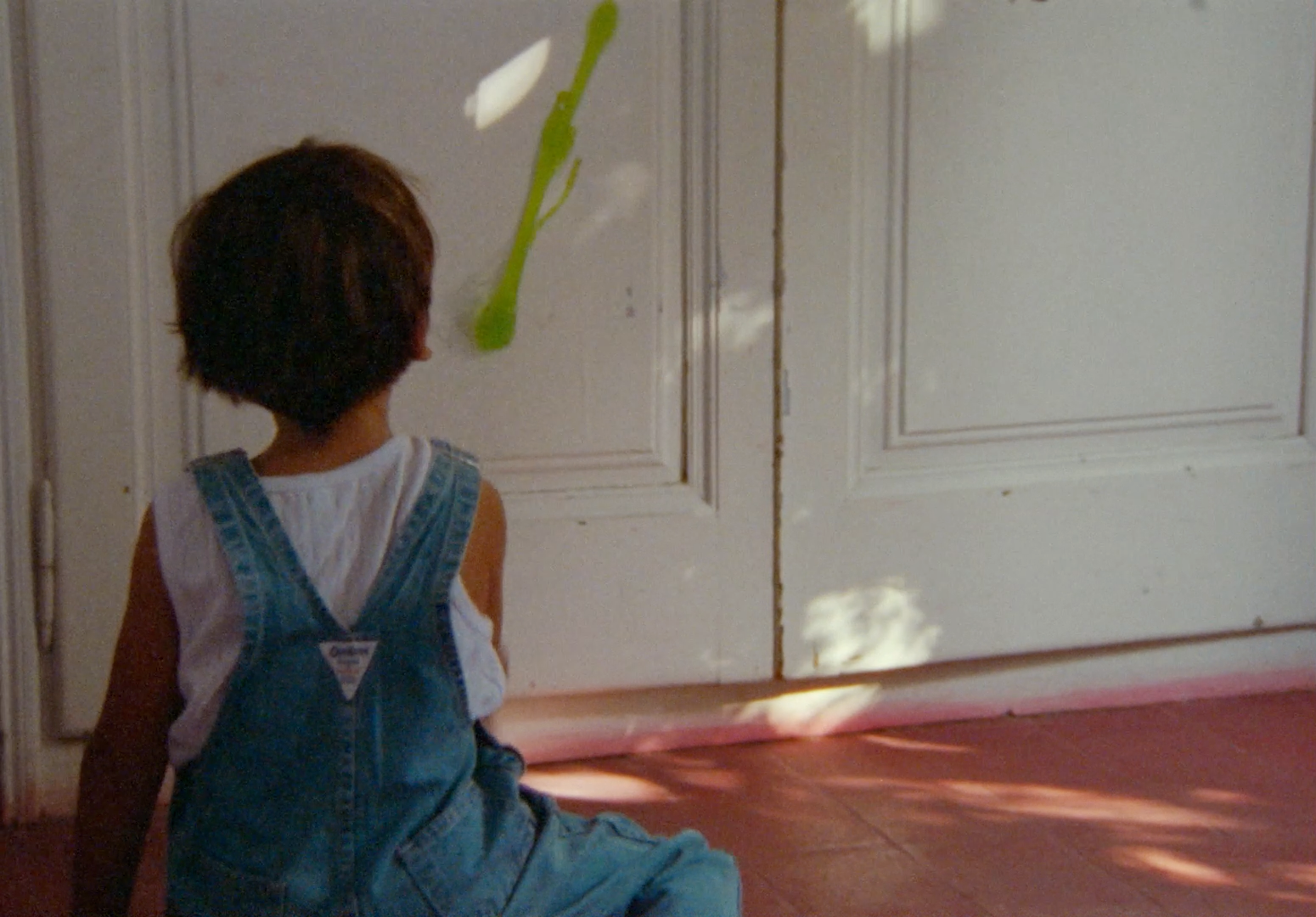 a little boy sitting on the floor in front of a door