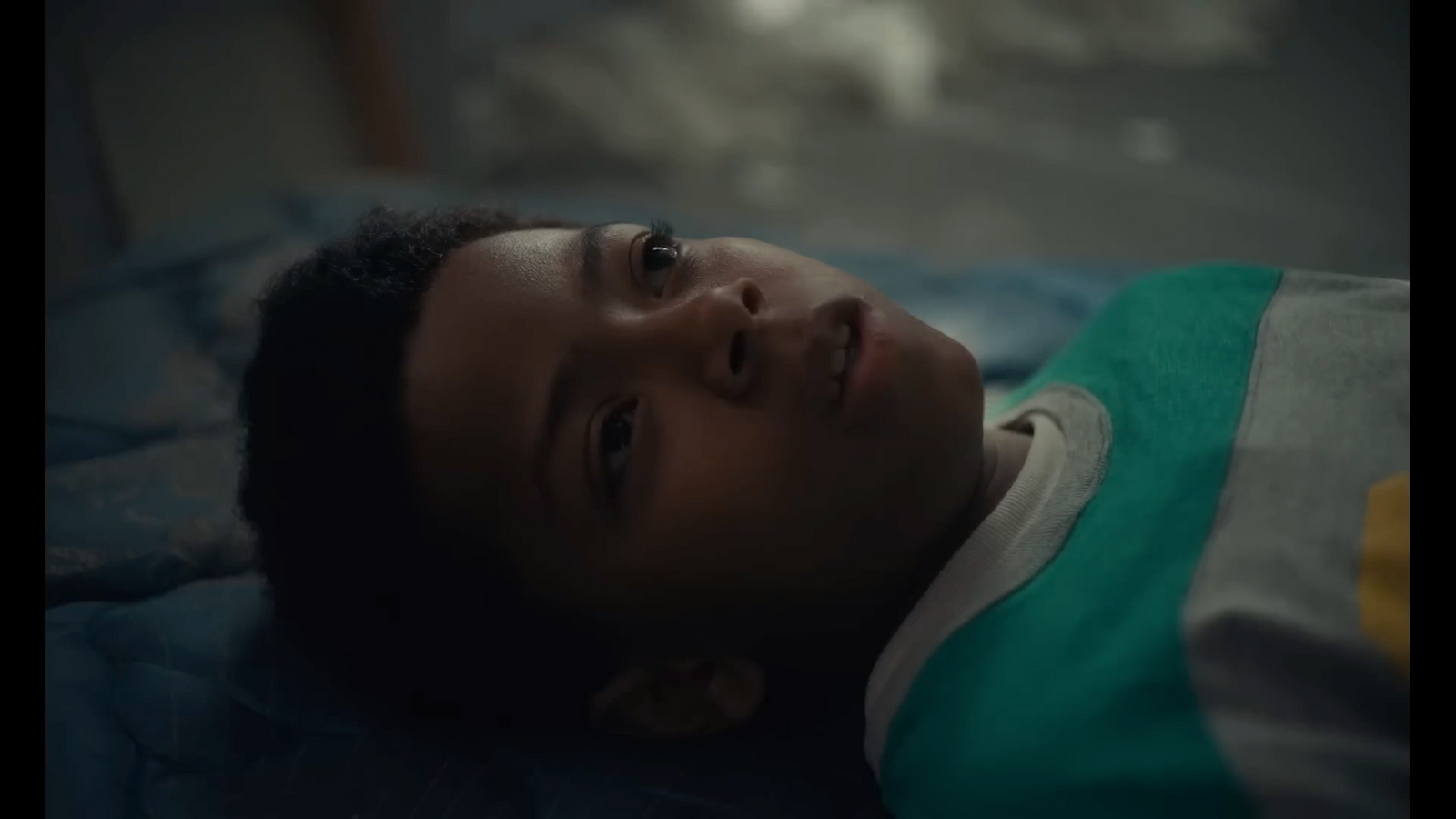 a young boy laying on top of a bed