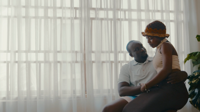 a man and woman sitting on a chair in front of a window