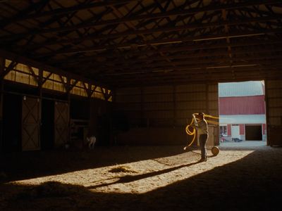 a person standing in a barn with a hose