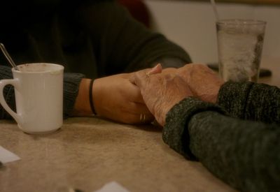 a close up of two people holding hands at a table