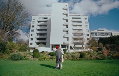 a man standing in the grass in front of a building