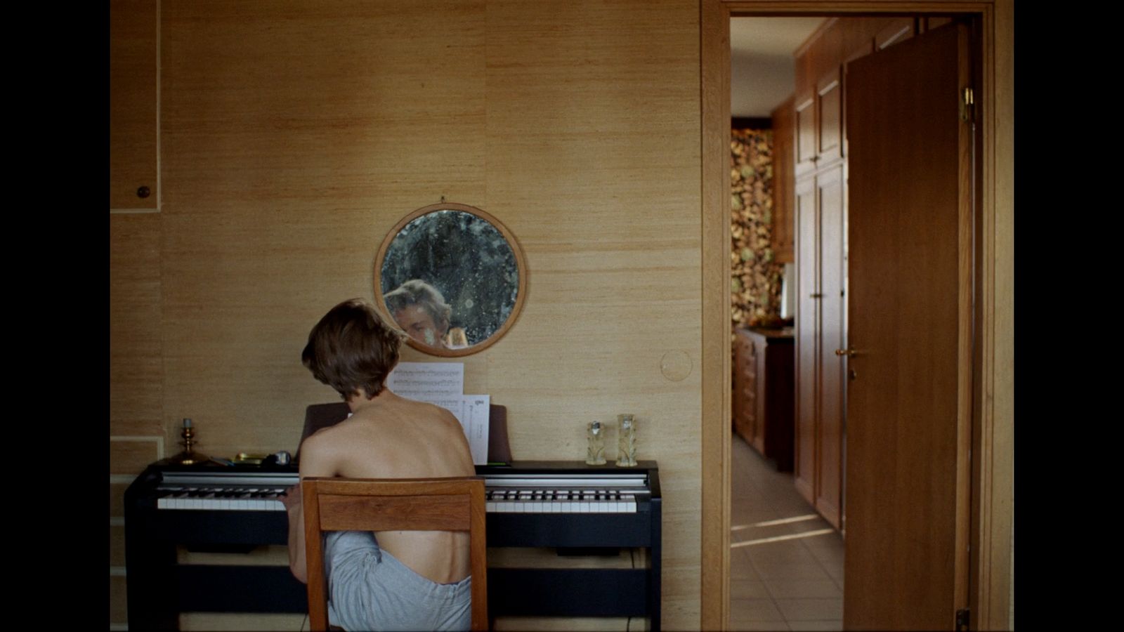 a woman sitting at a piano in front of a mirror