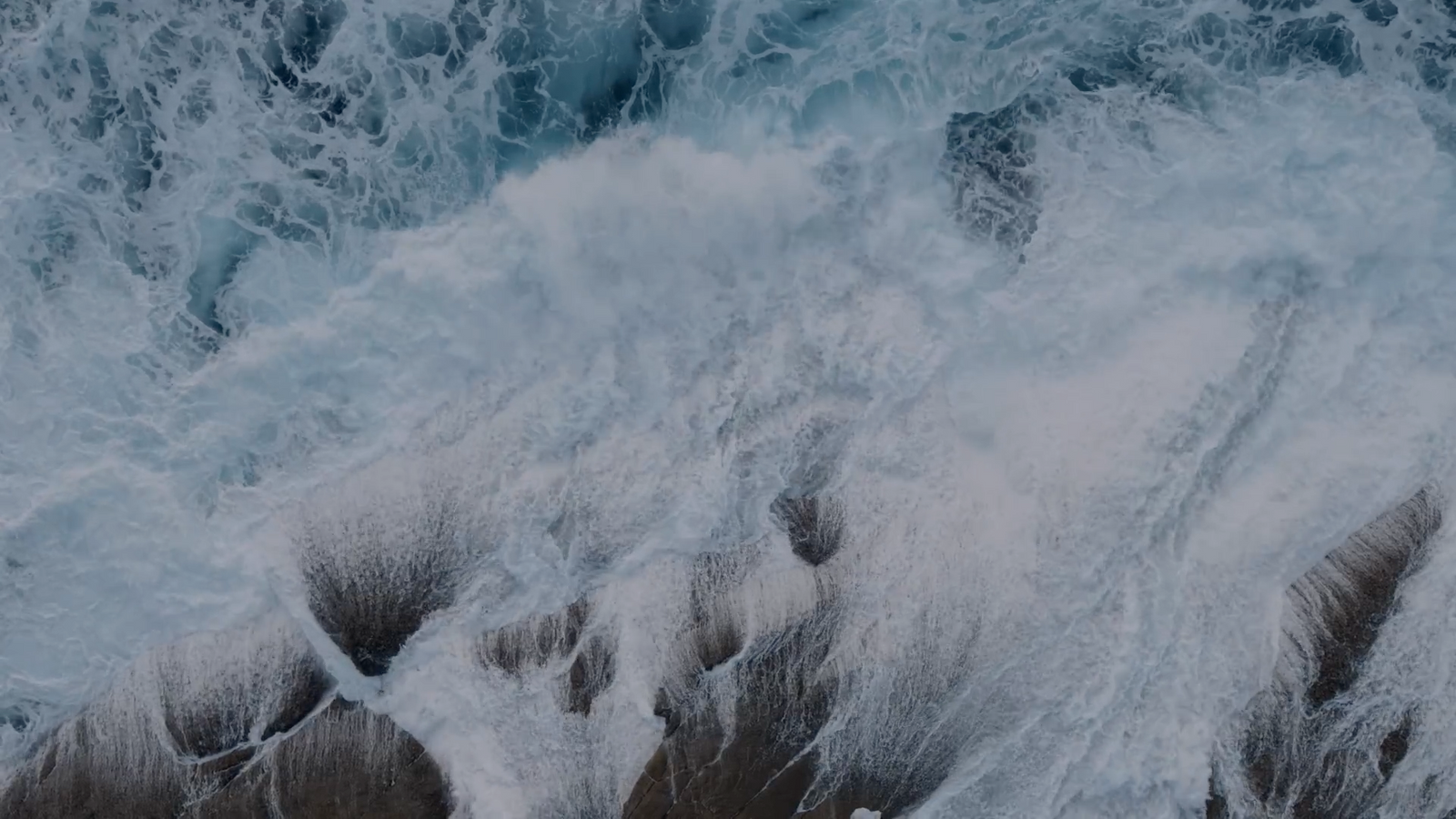 an aerial view of waves crashing on the beach