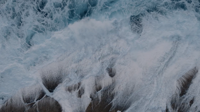 an aerial view of waves crashing on the beach