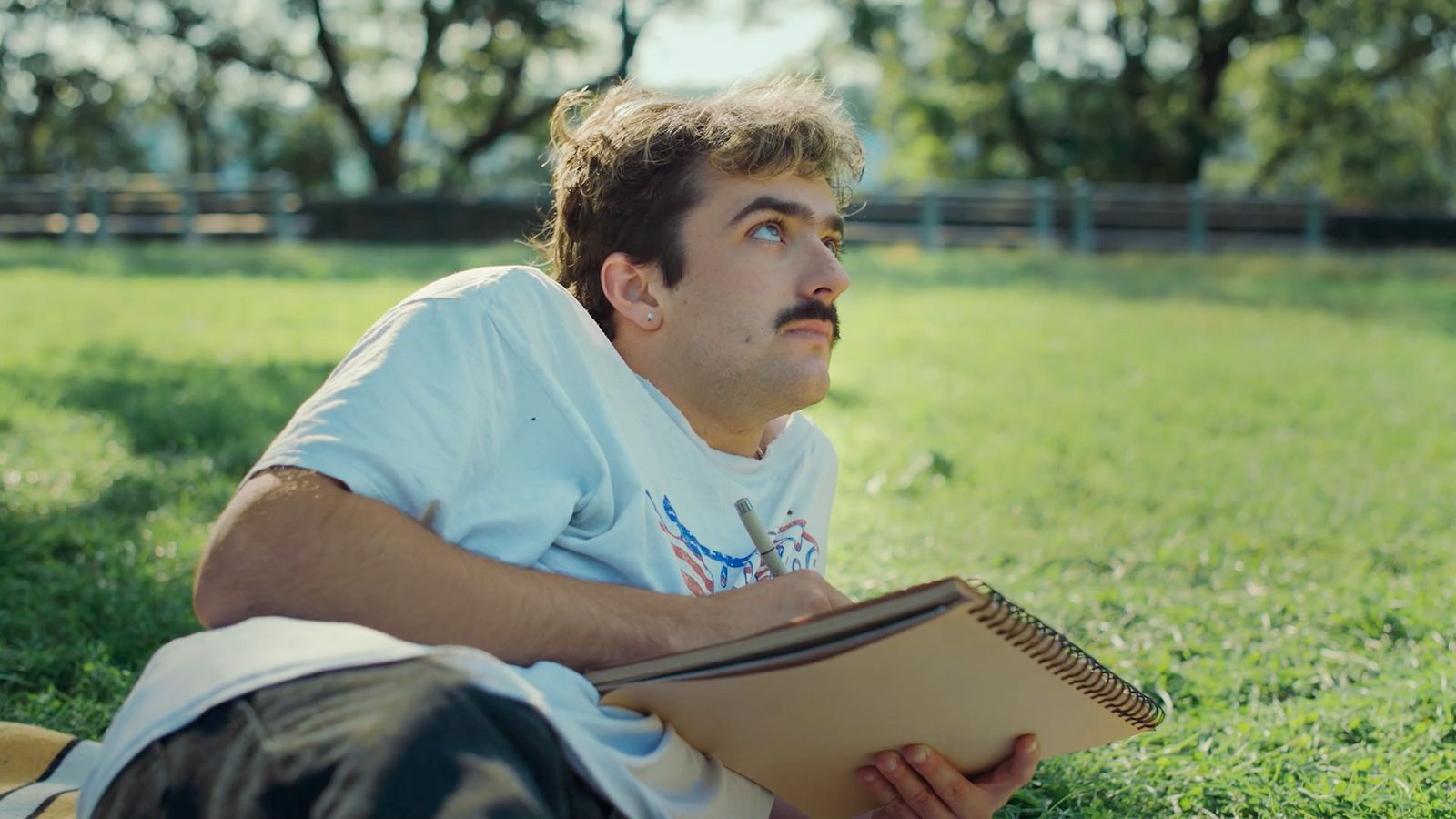 a man laying in the grass reading a book