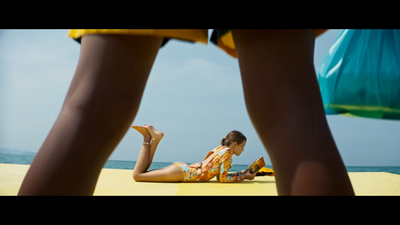 a woman laying on top of a beach next to the ocean