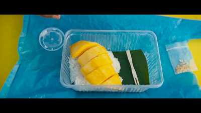 a plastic container filled with rice and mango slices