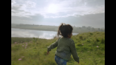 a little girl running across a lush green field