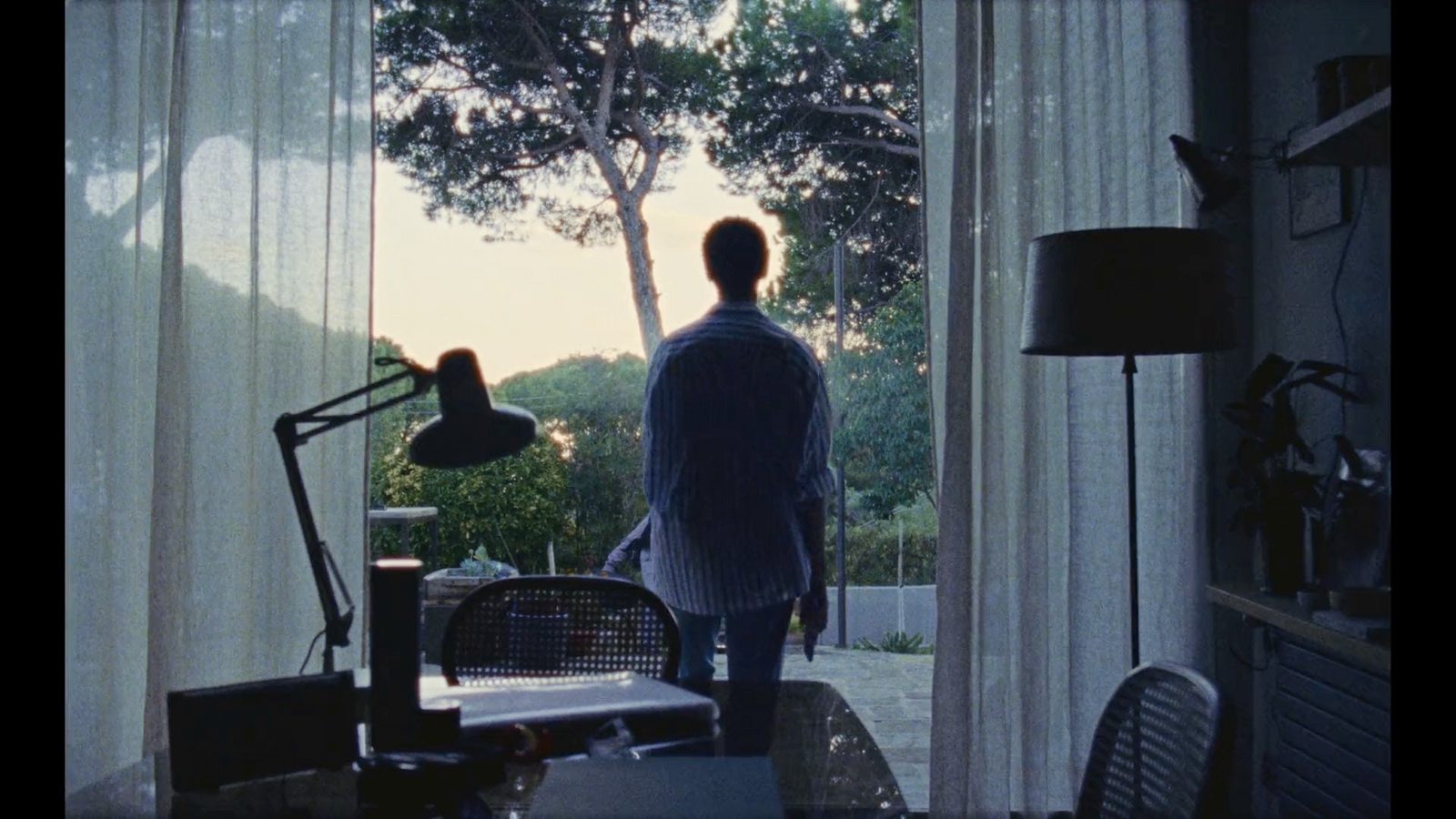 a man standing in a living room looking out a window