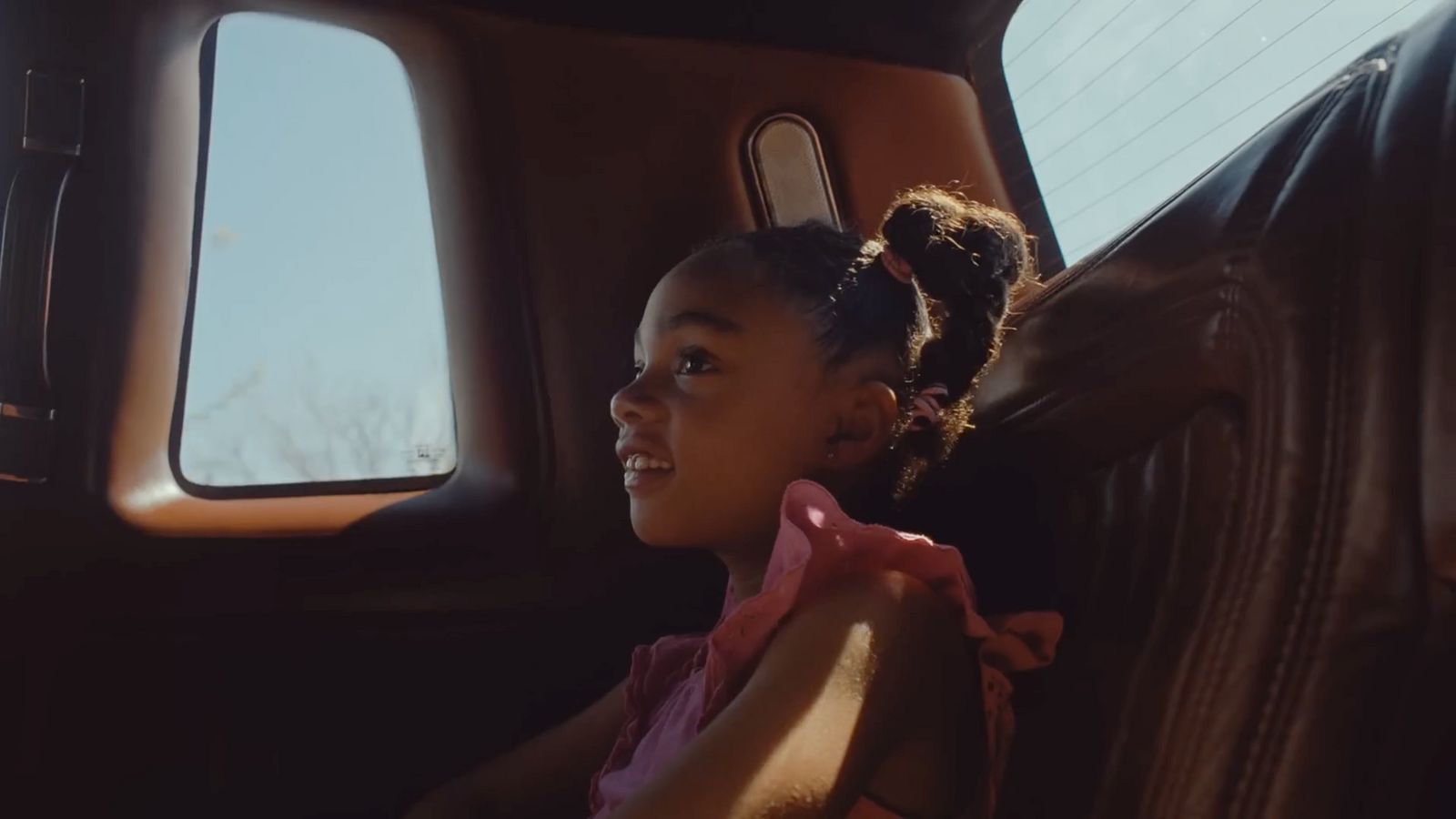 a little girl sitting in the back seat of a car