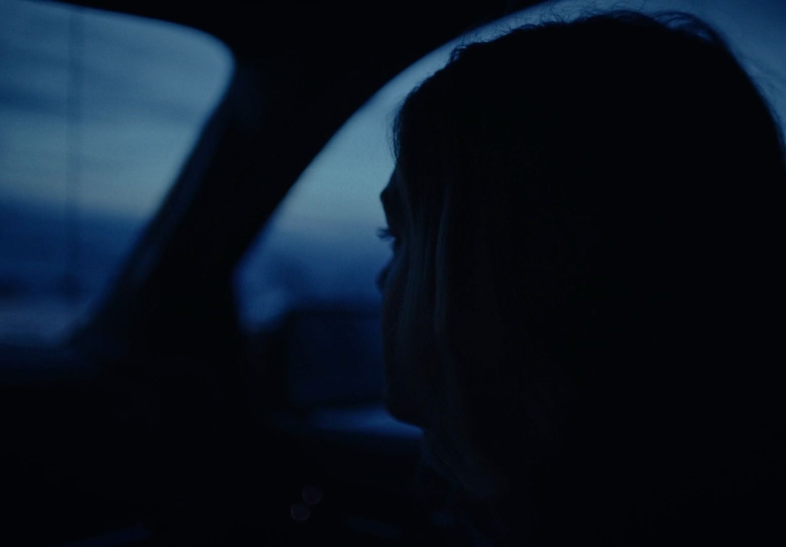 a woman sitting in a car in the dark