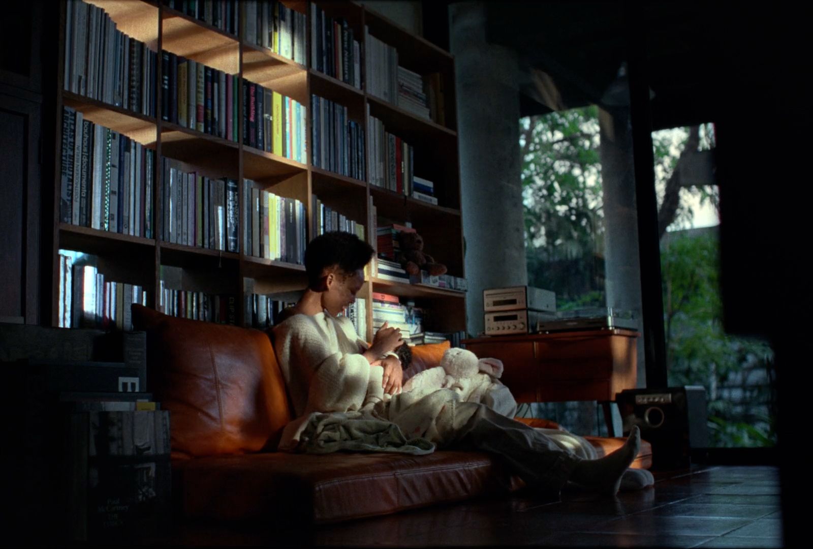 a man sitting on a couch in front of a book shelf