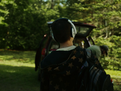 a man with a backpack and headphones standing in front of a car