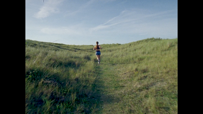 a woman is running through a grassy field