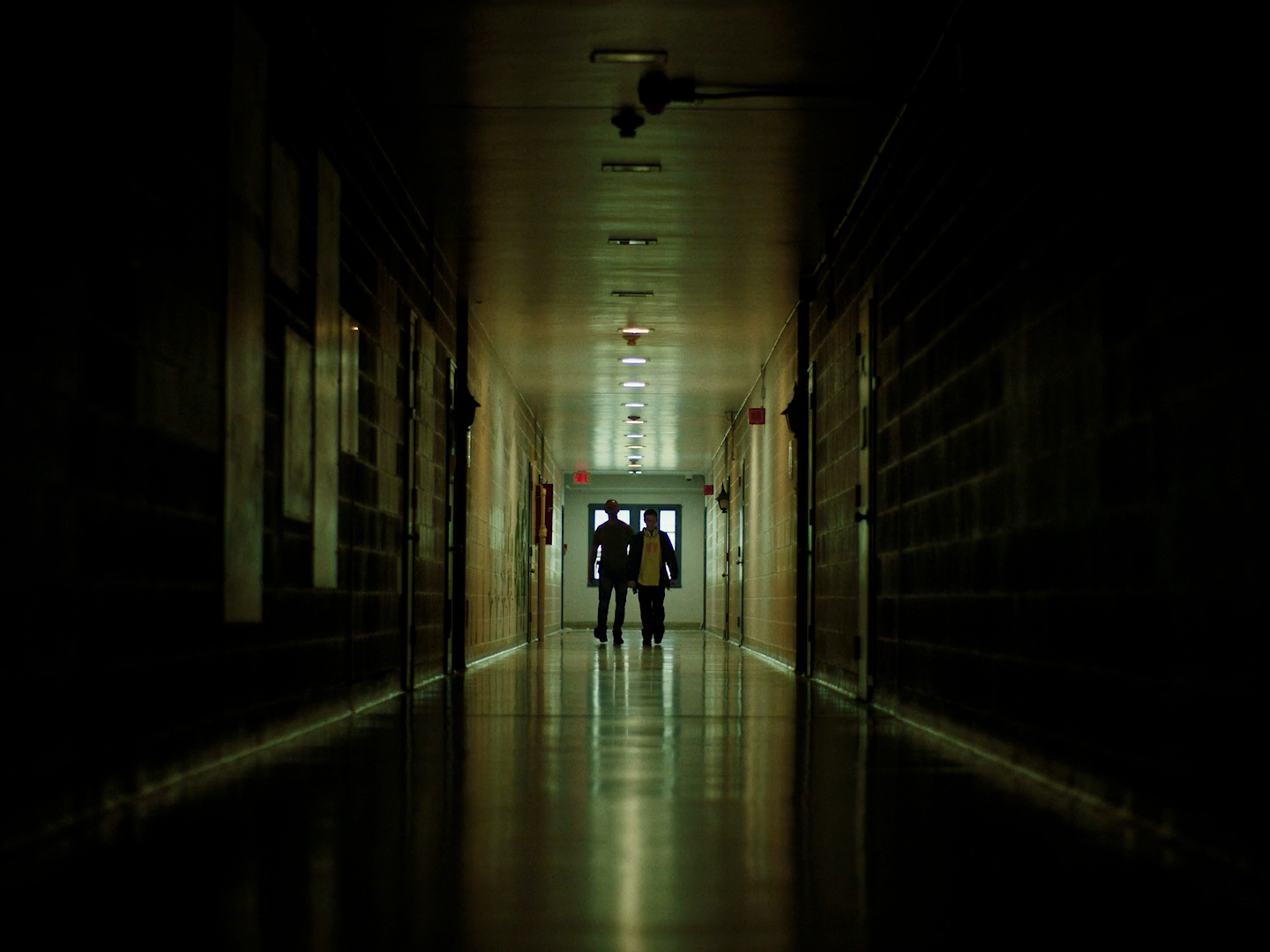 a couple of people walking down a long hallway