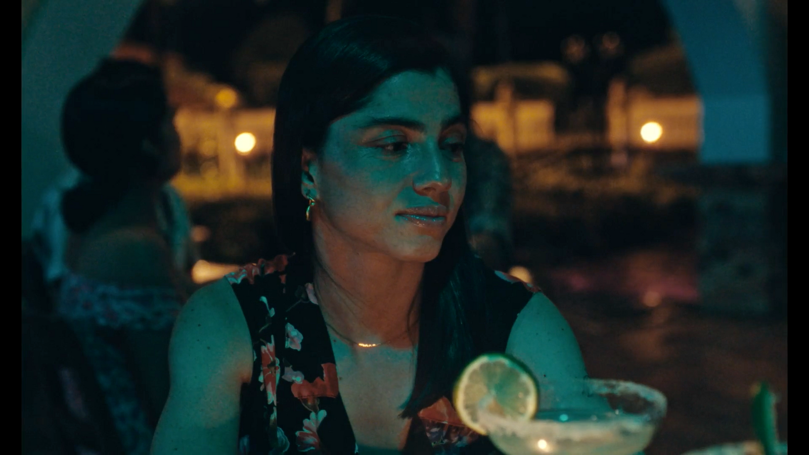 a woman sitting at a table with a drink in front of her