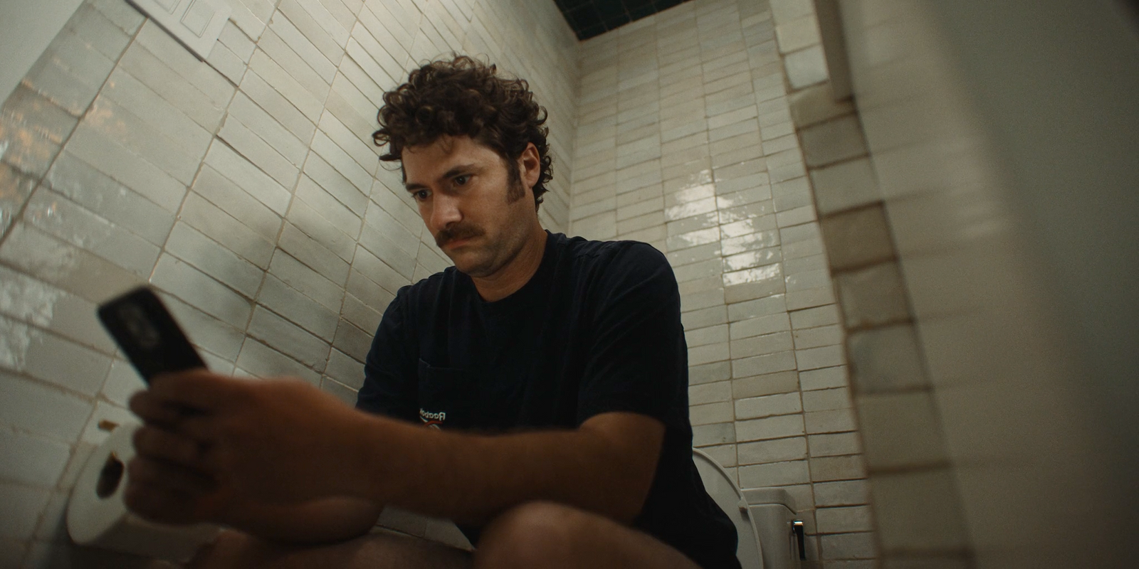 a man sitting on a toilet holding a cell phone