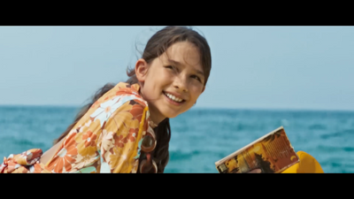 a young girl sitting on the beach reading a book