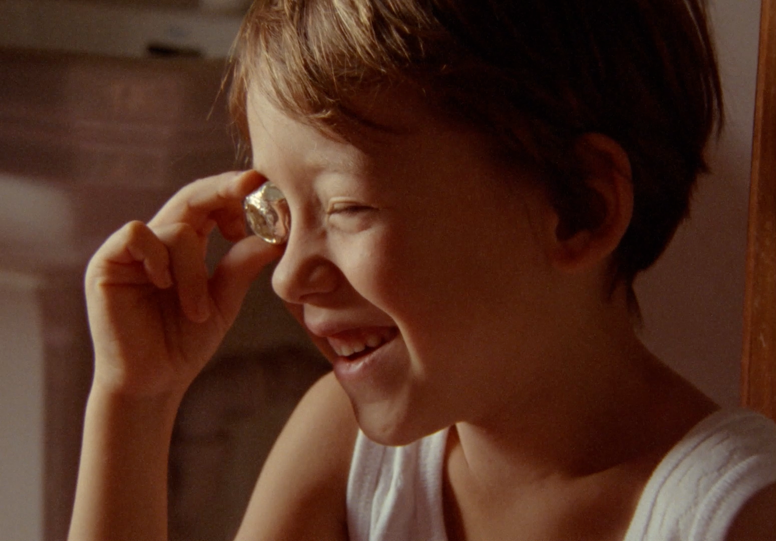 a young girl smiles as she holds a magnifying glass