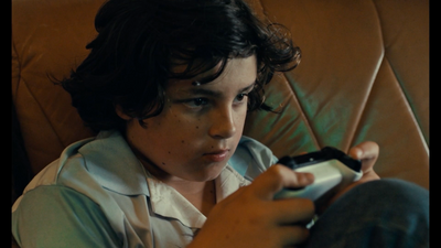 a young boy sitting on a couch holding a remote control