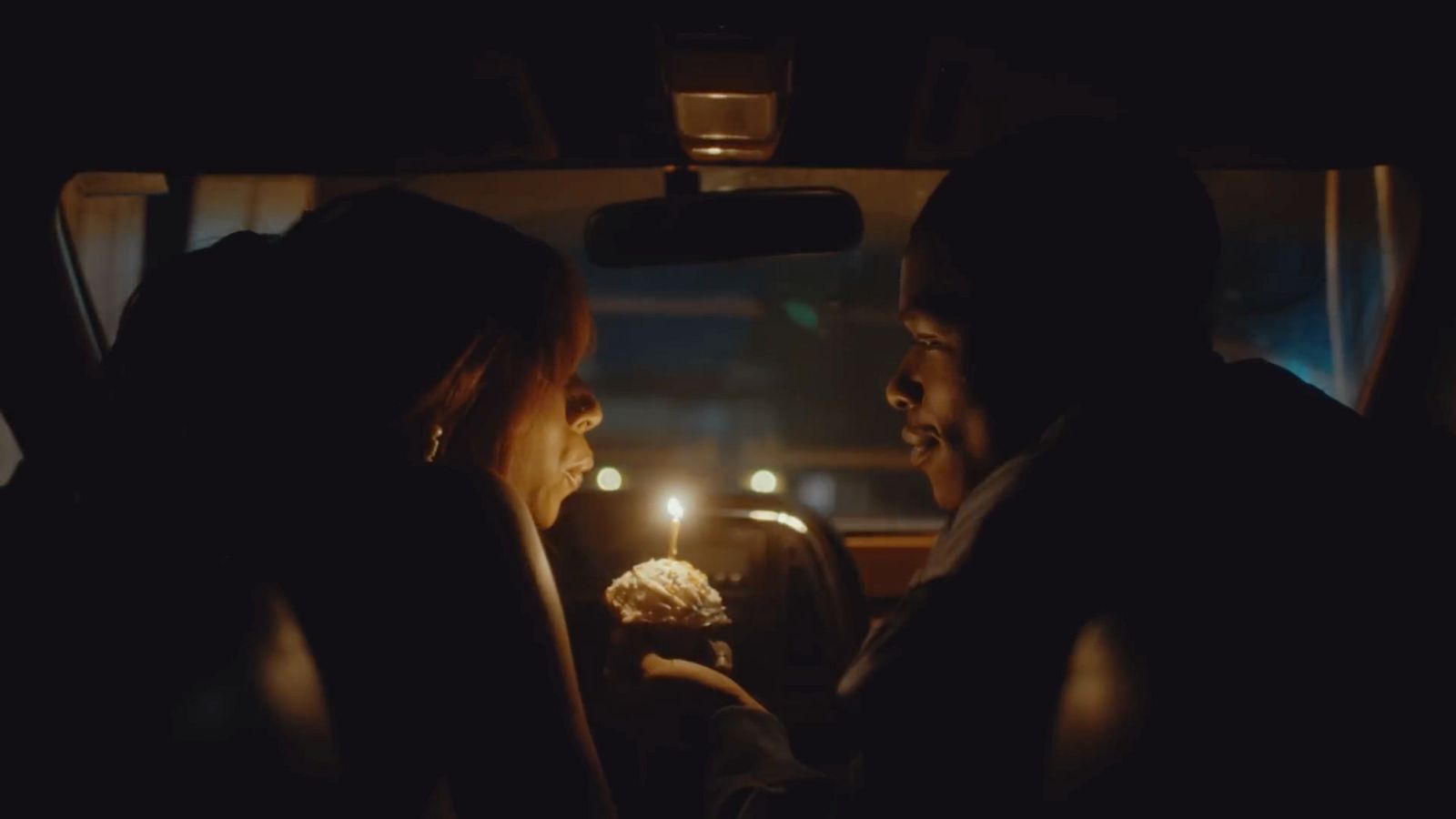 a couple of people sitting in a car with a cake