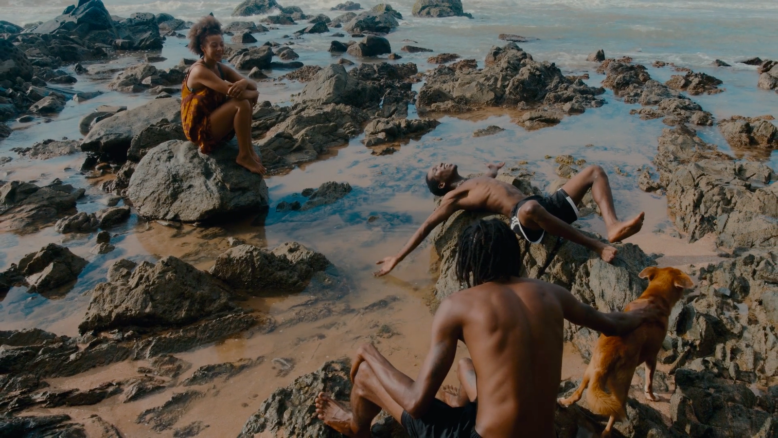 a group of people sitting on top of rocks near the ocean