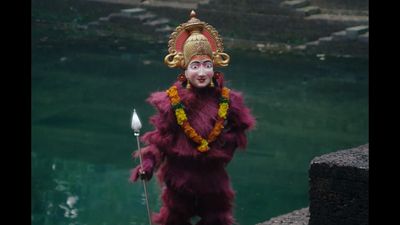 a man dressed in a costume standing next to a body of water