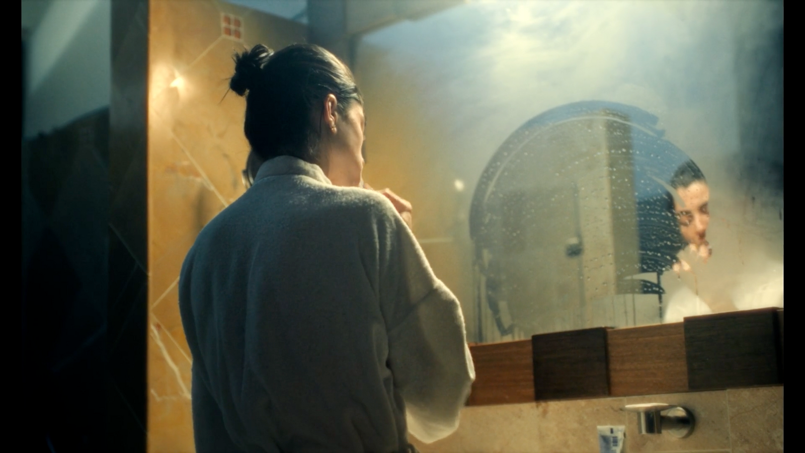 a woman standing in front of a bathroom mirror