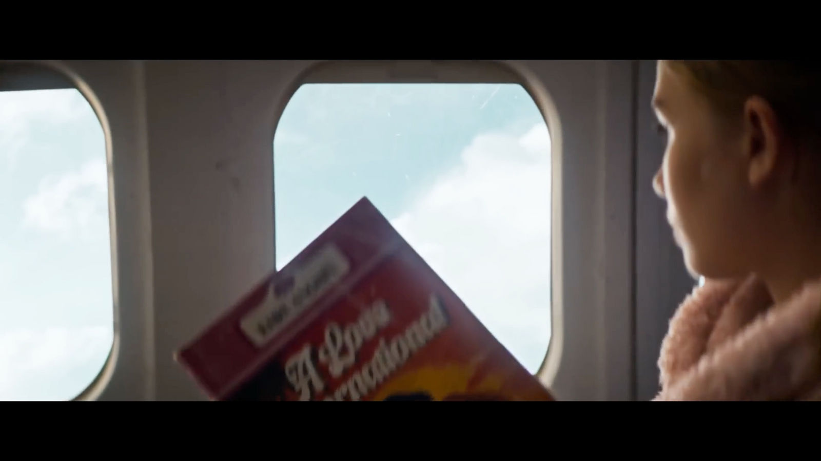 a woman looking out an airplane window at a book