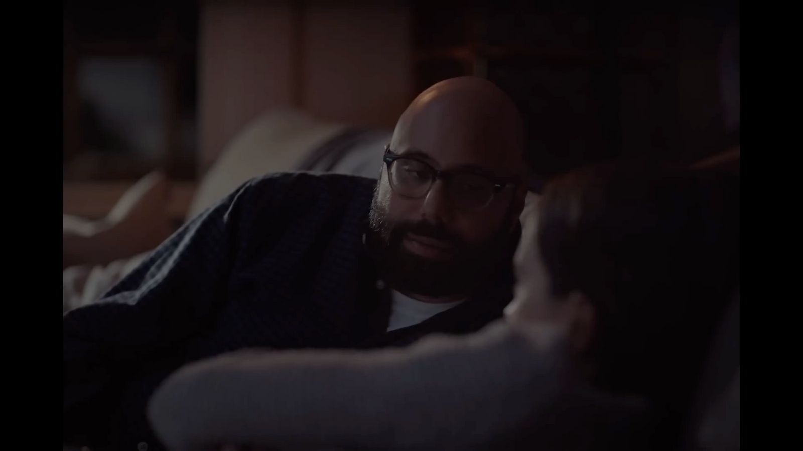 a man with a beard and glasses sitting on a couch