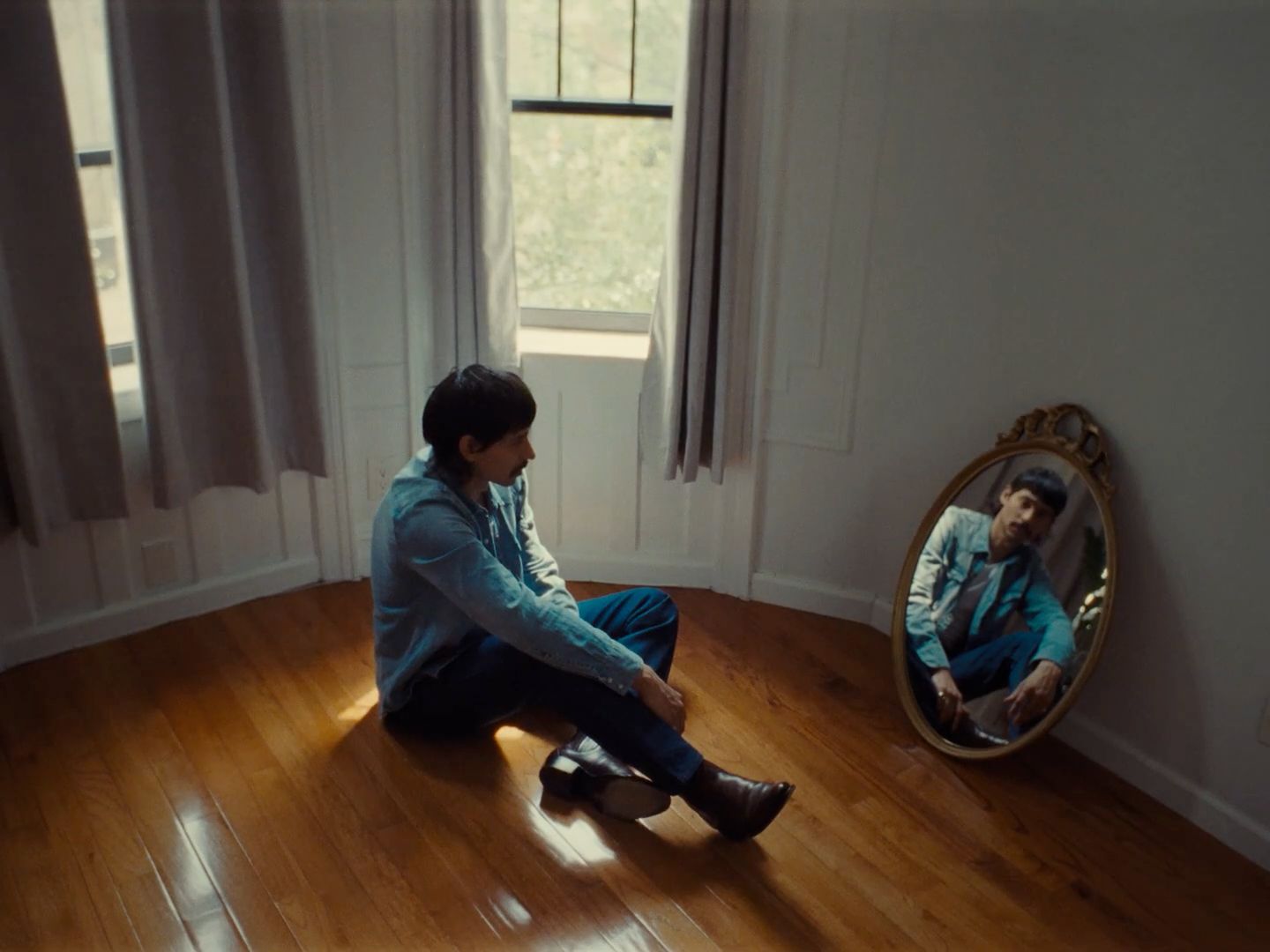 a man sitting on the floor in front of a mirror