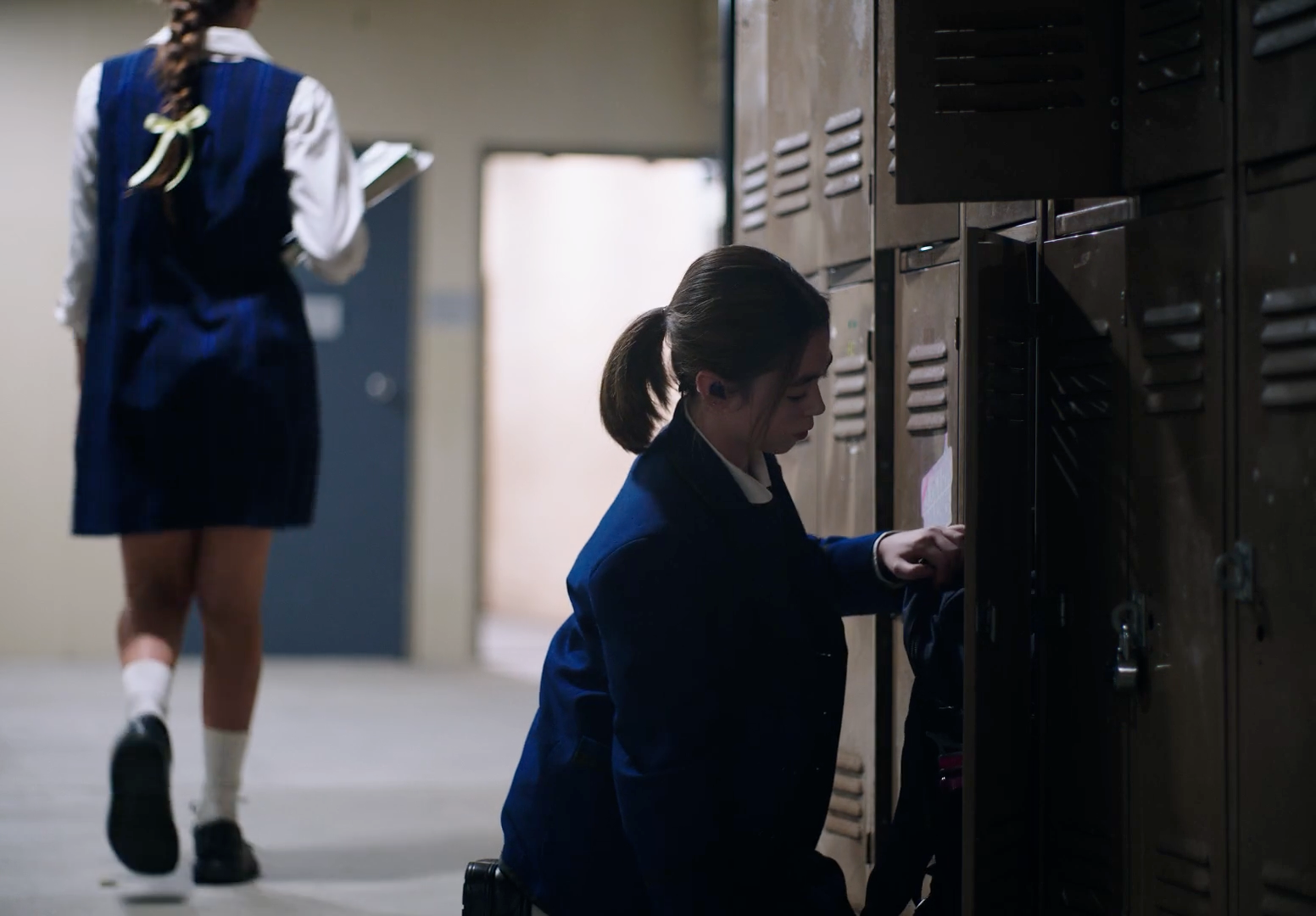 a woman in a school uniform is opening a locker