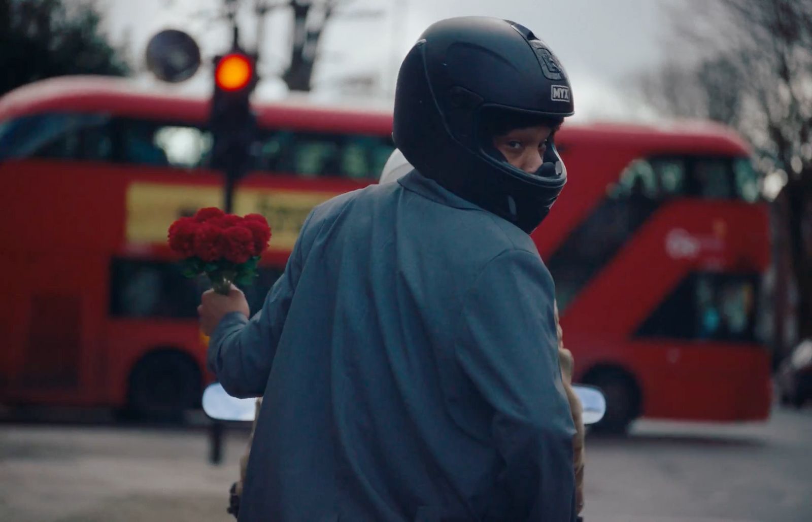 a man in a motorcycle helmet holding a red rose